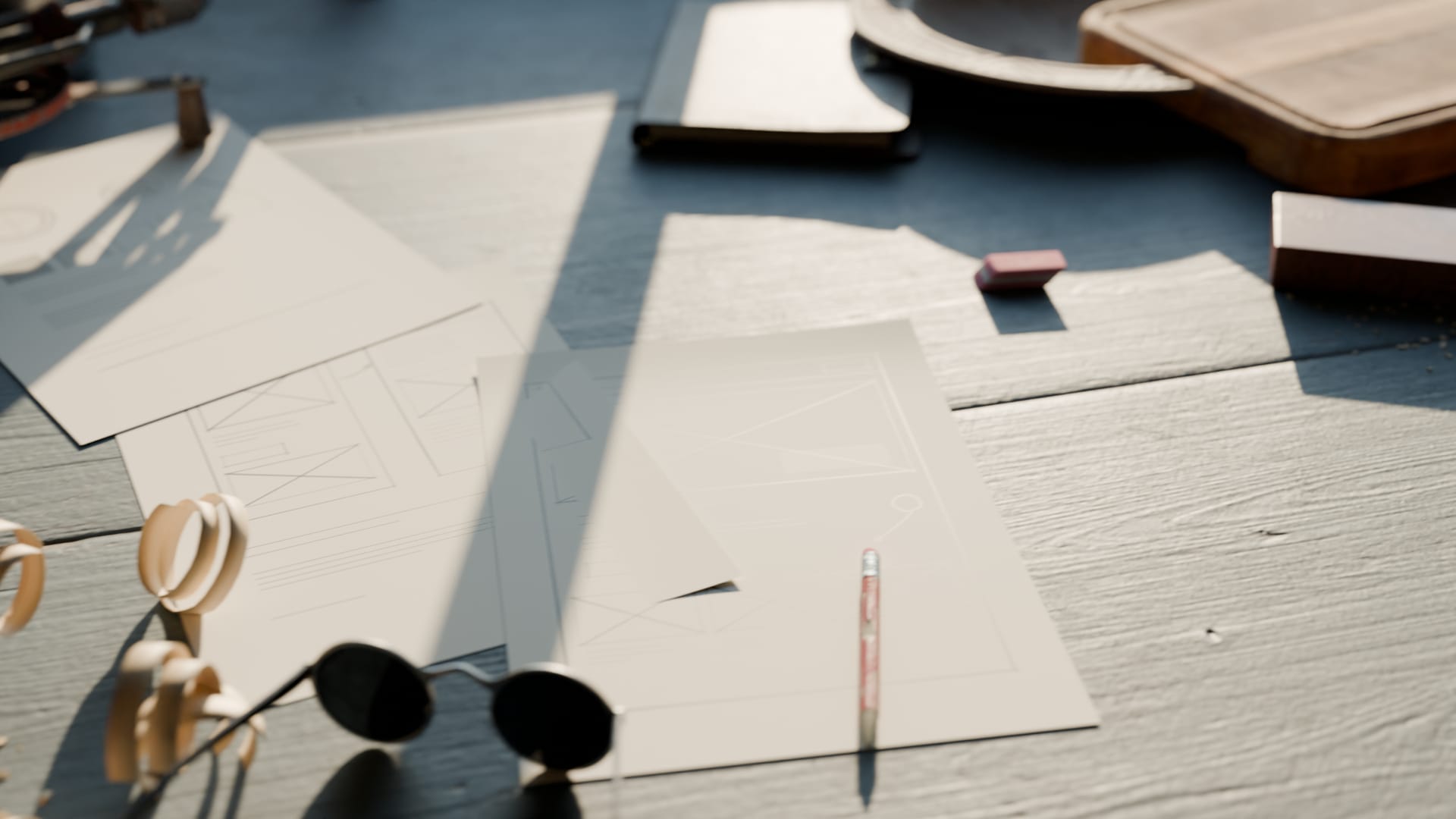 Pencil sketches of web page layouts on loose paper, with a pencil, an eraser and a pair of round glasses.