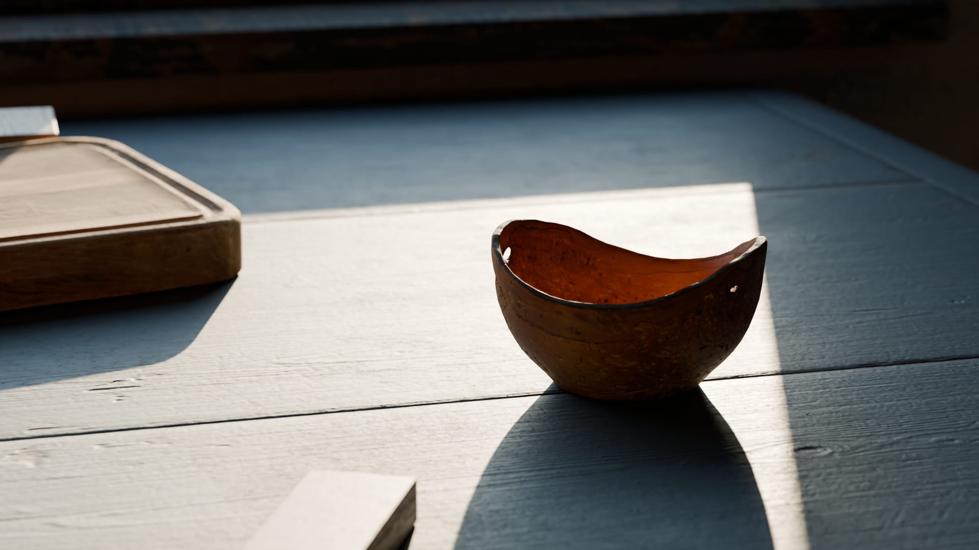 A small hand carved wooden bowl resting in a patch of late afternoon sun on the workbench.